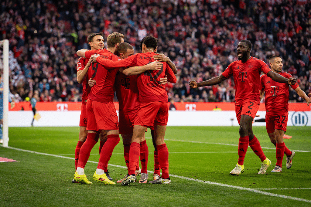 Einige Bayern Spieler jubeln und liegen sich in den Armen nach einem Tor in der Allianz Arena in München, Deutschland.