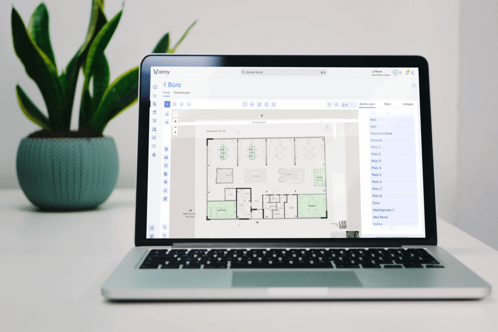 Ein Notebook, das geöffnet ist und das Buchungstool anny zeigt. Im Hintergrund eine Zimmerpflanze in einem Topf.